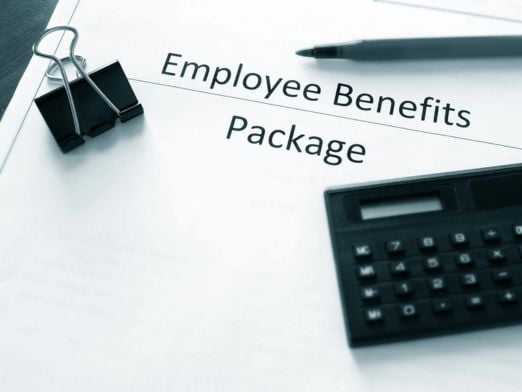 Employee Benefits Package with a pen, paperclip and calculator resting on top