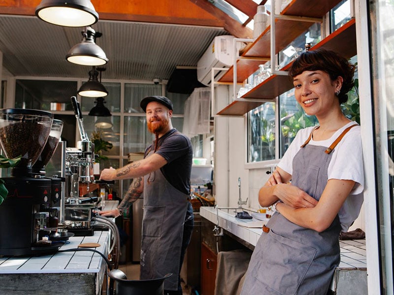Baristas working in a coffee shop that is covered by small business health insurance in Palm Beach, FL.