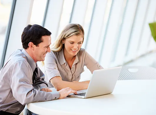 Two employees looking at a laptop